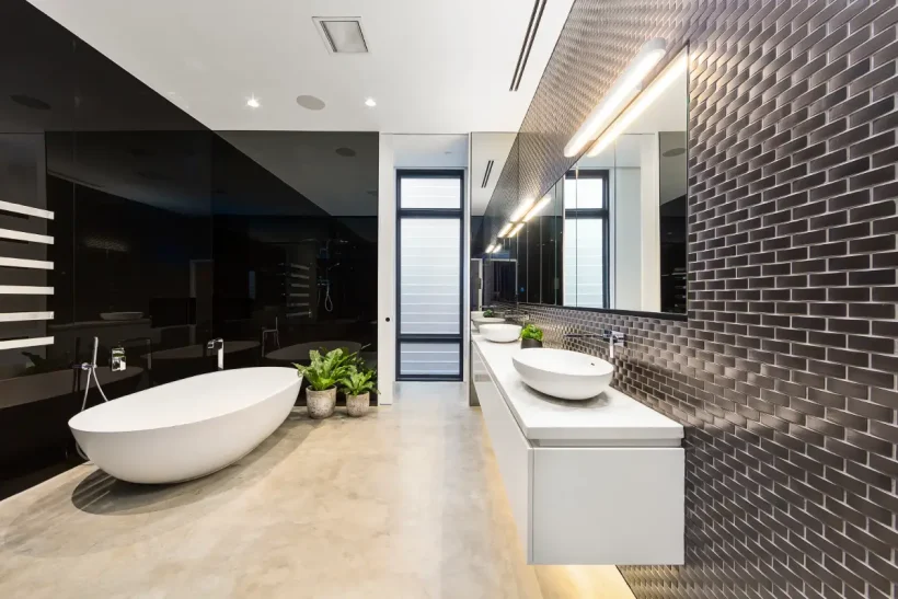 The image showcases a modern bathroom interior. The room features a combination of smooth concrete floors and a brick tile wall pattern.